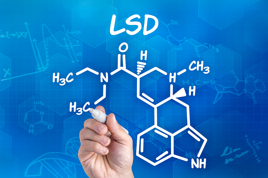 hand with pen drawing the chemical formula of lsd